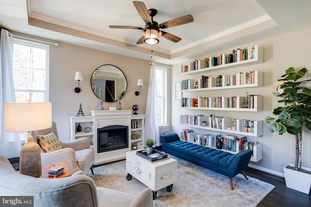 sitting room with crown molding, hardwood / wood-style flooring, a raised ceiling, and a healthy amount of sunlight