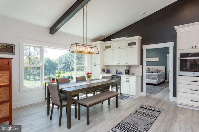 dining room with lofted ceiling with beams, light hardwood / wood-style flooring, a chandelier, and beverage cooler