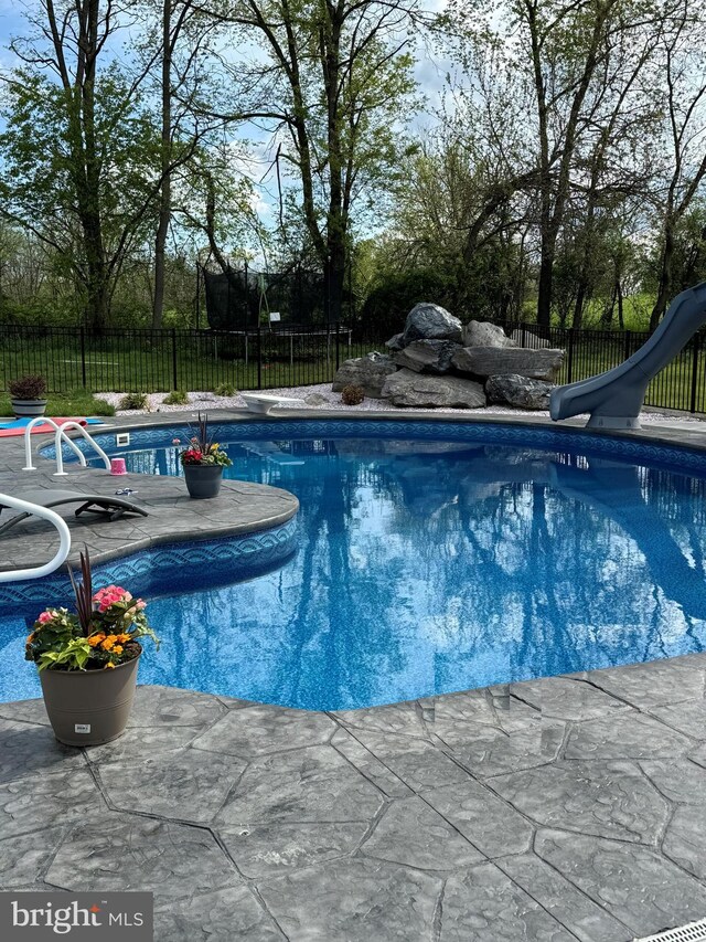 view of swimming pool featuring a water slide, a diving board, and a patio area