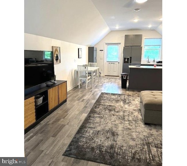 living room featuring lofted ceiling, hardwood / wood-style floors, and sink