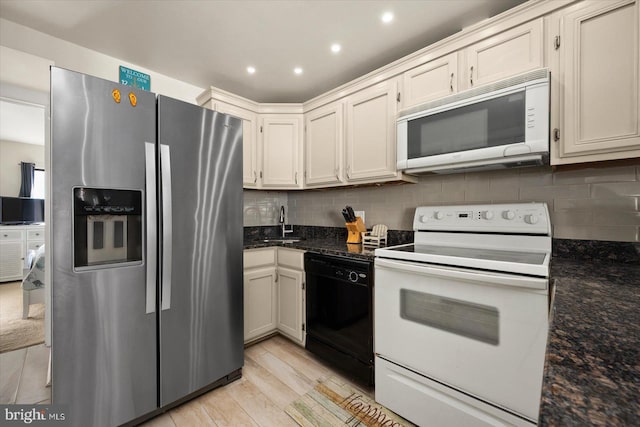 kitchen with tasteful backsplash, light hardwood / wood-style flooring, dark stone countertops, sink, and white appliances