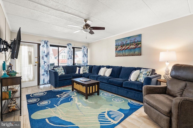 living room with a textured ceiling, wood-type flooring, and ceiling fan