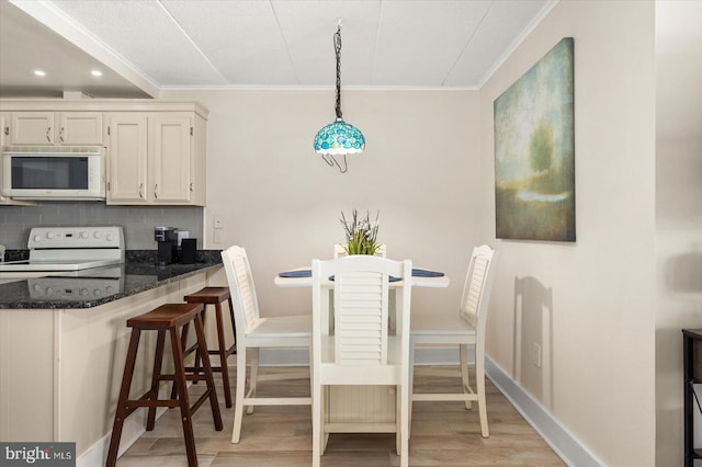 dining area featuring ornamental molding and light hardwood / wood-style floors