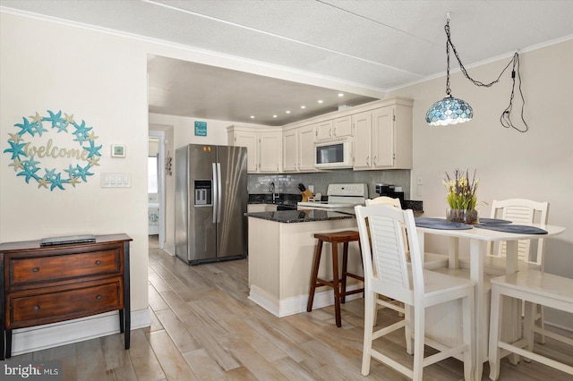 kitchen featuring white appliances, tasteful backsplash, light wood-type flooring, kitchen peninsula, and hanging light fixtures