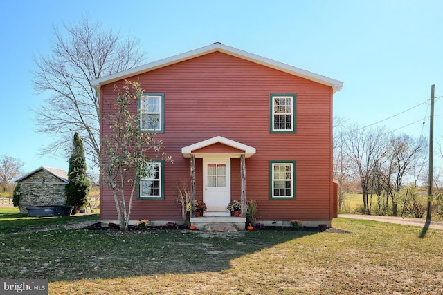 view of front of house featuring a front yard and a storage shed