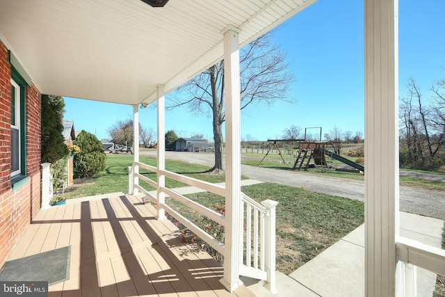 wooden terrace with a playground and a yard