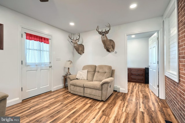 interior space with a baseboard radiator, hardwood / wood-style floors, and brick wall