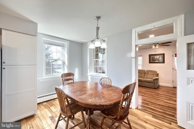 dining area with ceiling fan with notable chandelier, a baseboard radiator, and light hardwood / wood-style floors