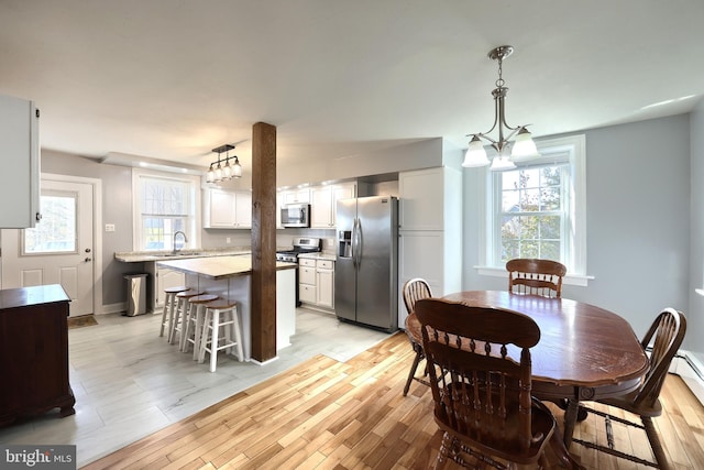 dining area featuring light hardwood / wood-style flooring, a chandelier, sink, and plenty of natural light