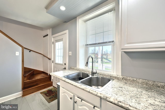 kitchen with white cabinetry, sink, and light stone counters