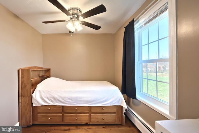 bedroom featuring dark hardwood / wood-style flooring, ceiling fan, and a baseboard radiator