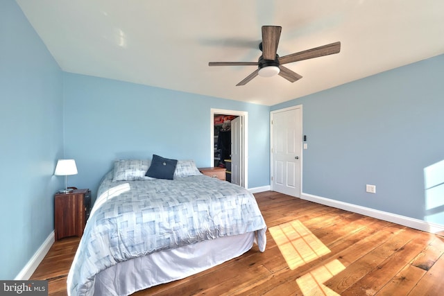 bedroom featuring a closet, a spacious closet, wood-type flooring, and ceiling fan