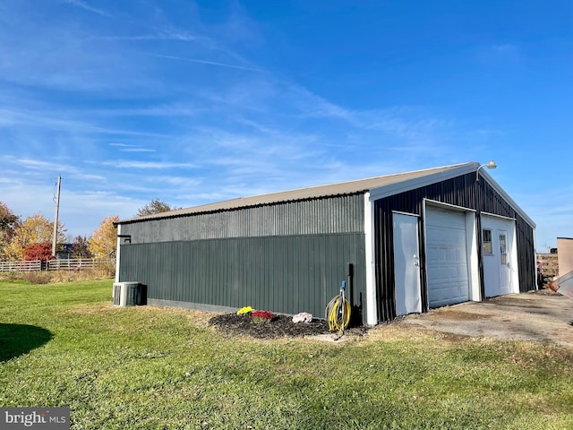 view of outdoor structure with central AC unit, a garage, and a yard