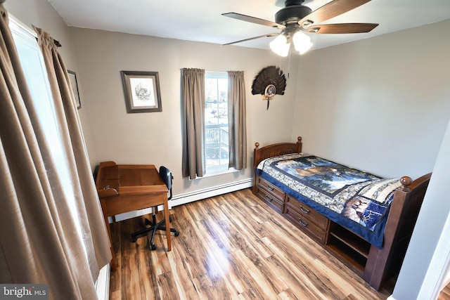 bedroom featuring a baseboard heating unit, ceiling fan, and light hardwood / wood-style flooring