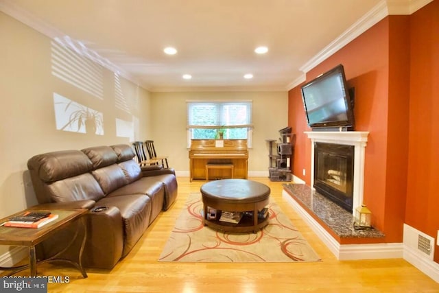 living room featuring ornamental molding, a high end fireplace, and light wood-type flooring