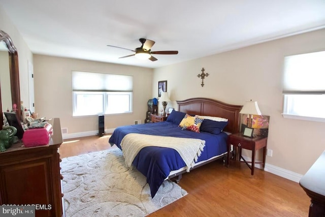 bedroom featuring multiple windows, hardwood / wood-style floors, and ceiling fan