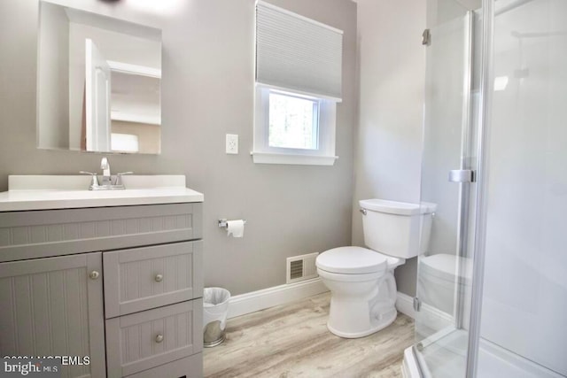 bathroom featuring vanity, a shower with shower door, wood-type flooring, and toilet