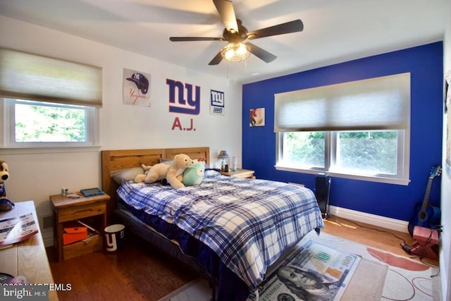 bedroom with multiple windows, wood-type flooring, and ceiling fan