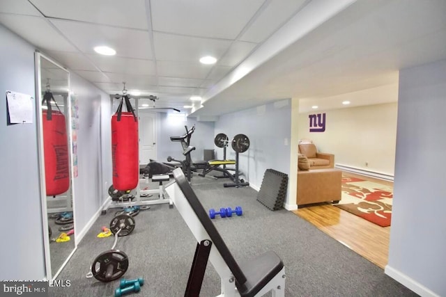 exercise area with a drop ceiling, hardwood / wood-style floors, and a baseboard heating unit