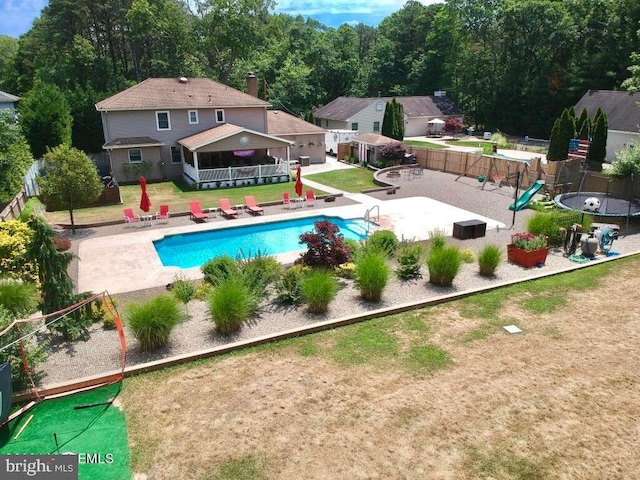 view of swimming pool featuring a trampoline, a patio area, and a lawn