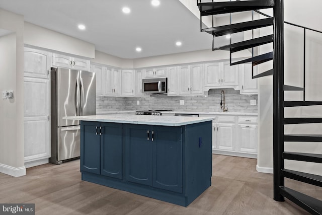 kitchen with stainless steel appliances, white cabinetry, and a center island