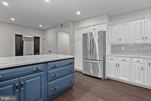 kitchen with white cabinets, blue cabinetry, dark wood-type flooring, and stainless steel refrigerator