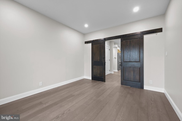 unfurnished bedroom featuring hardwood / wood-style flooring and a barn door