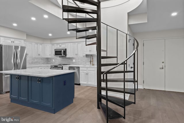 kitchen featuring light wood-type flooring, a center island, appliances with stainless steel finishes, and white cabinets