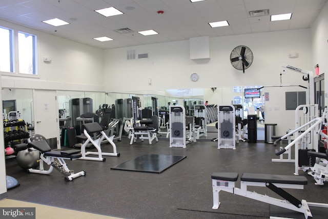 workout area with a towering ceiling and a paneled ceiling