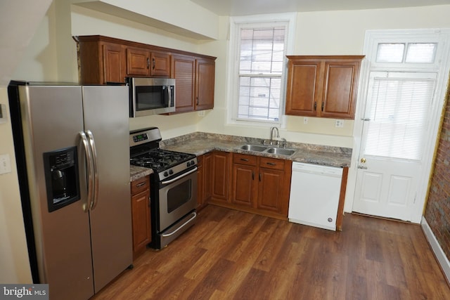 kitchen with sink, appliances with stainless steel finishes, dark hardwood / wood-style floors, and dark stone counters