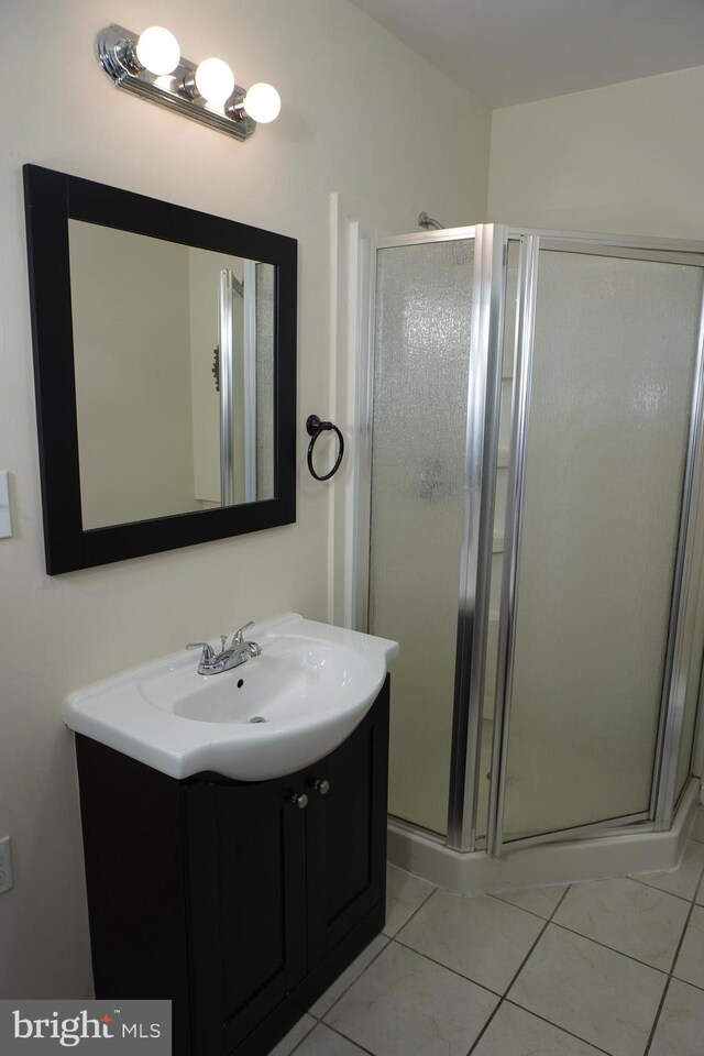 bathroom with vanity, a shower with shower door, and tile patterned flooring