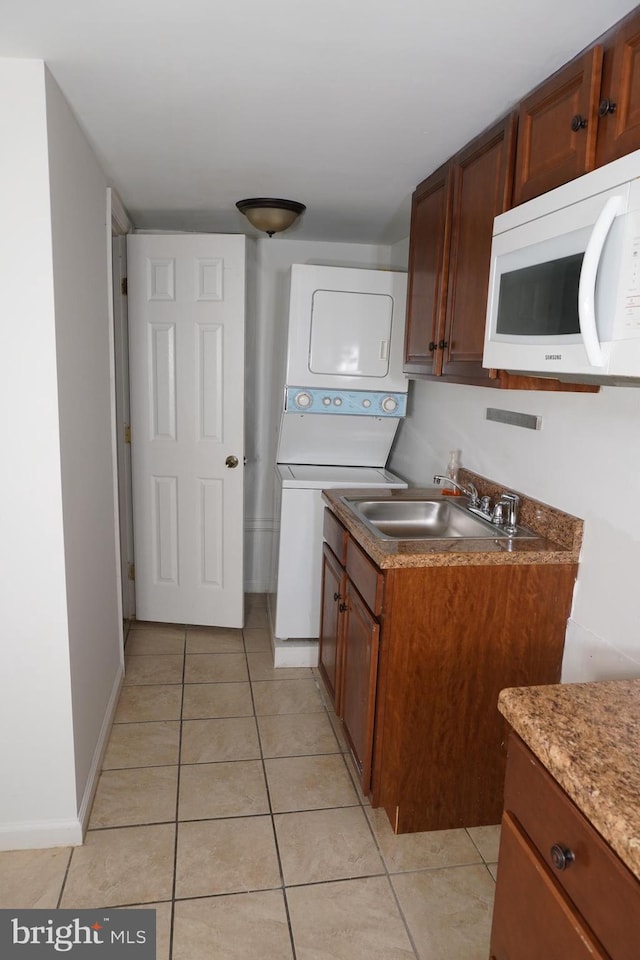 kitchen with sink, light tile patterned flooring, and stacked washing maching and dryer