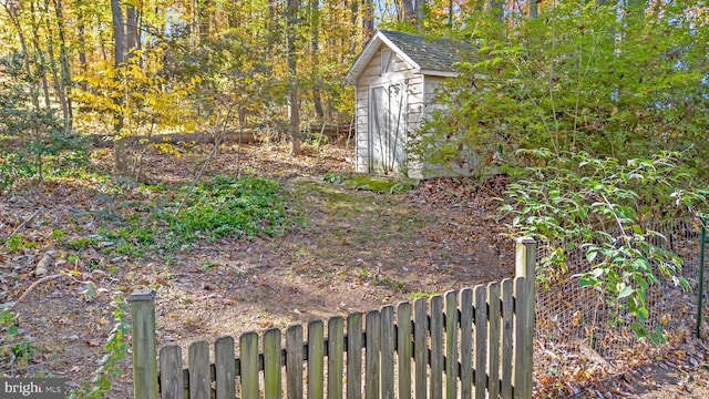 view of yard featuring a shed, fence, and an outdoor structure