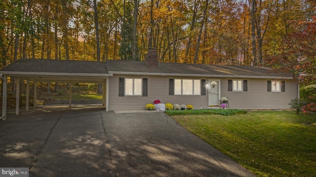 ranch-style house with aphalt driveway, a chimney, an attached carport, and a front yard