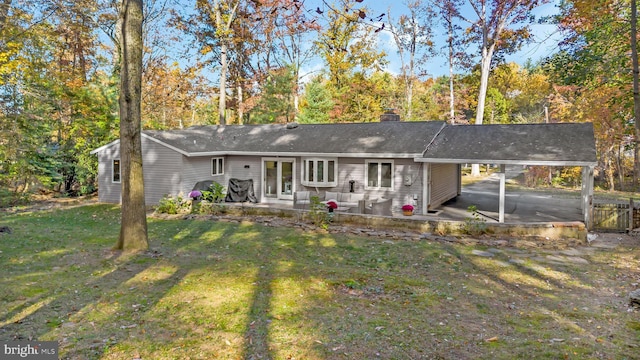 ranch-style house featuring a patio, a carport, a chimney, and a front yard