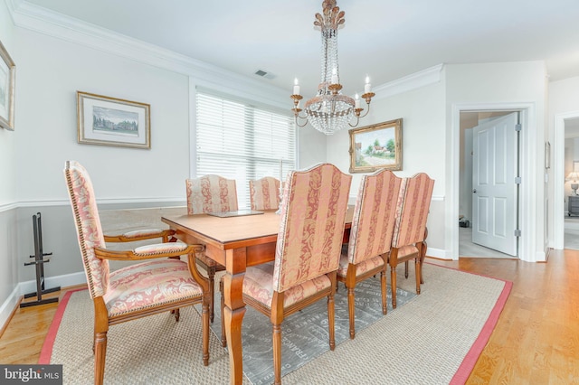 dining space featuring a notable chandelier, light hardwood / wood-style flooring, and ornamental molding