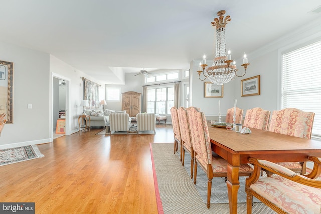 dining space with ornamental molding, light wood-type flooring, and ceiling fan with notable chandelier