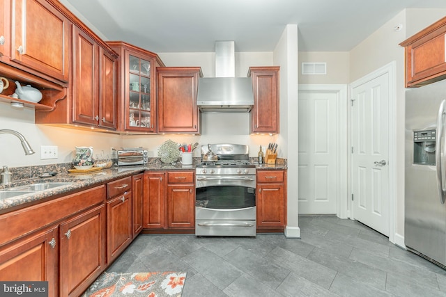 kitchen featuring stainless steel appliances, wall chimney exhaust hood, sink, and dark stone counters