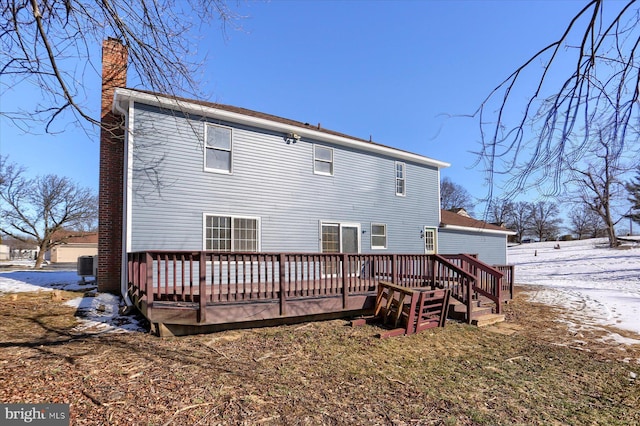 snow covered back of property with a wooden deck and central air condition unit