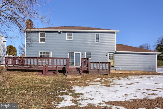 snow covered back of property featuring a wooden deck