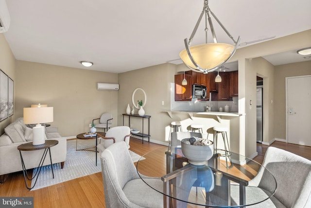 dining space featuring a wall unit AC and light hardwood / wood-style flooring