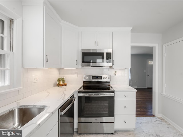 kitchen featuring white cabinets, light stone countertops, appliances with stainless steel finishes, and tasteful backsplash