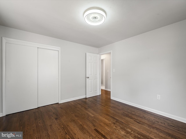 unfurnished bedroom featuring dark wood-type flooring and a closet