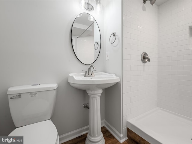 bathroom featuring toilet, sink, hardwood / wood-style floors, and tiled shower