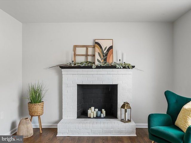 living area with a brick fireplace and dark wood-type flooring