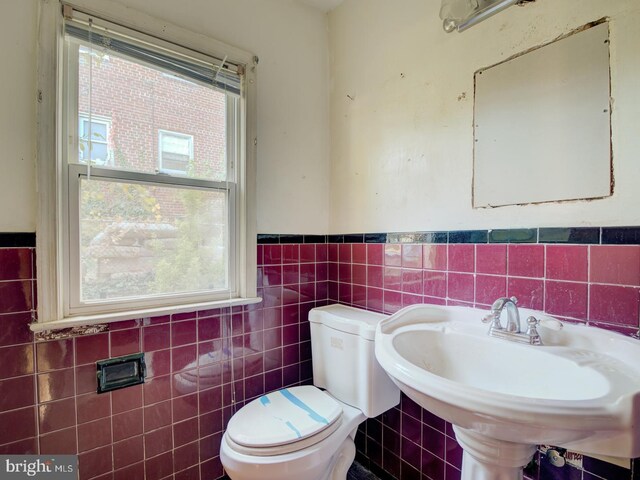 bathroom with toilet, tile walls, and sink