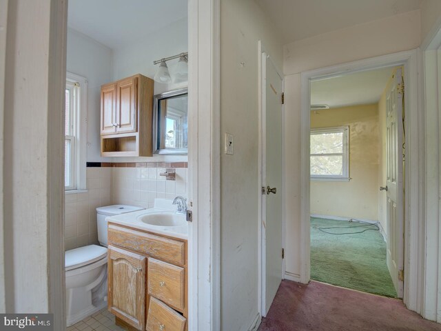 bathroom featuring vanity, toilet, and tile walls