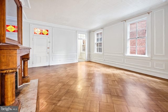 foyer entrance with ornamental molding and light parquet flooring