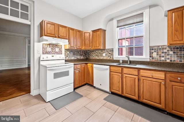 kitchen with backsplash, sink, light hardwood / wood-style floors, and white appliances