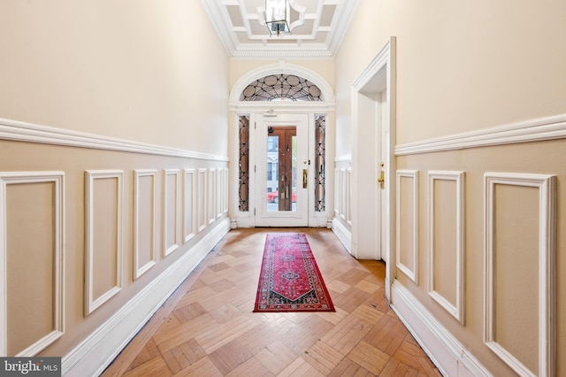 foyer featuring light parquet flooring, ornamental molding, and an inviting chandelier